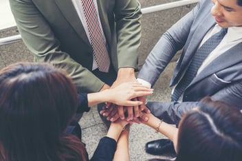 colaboradores representando com as mãos sobrepostas os pilares do programa de compliance